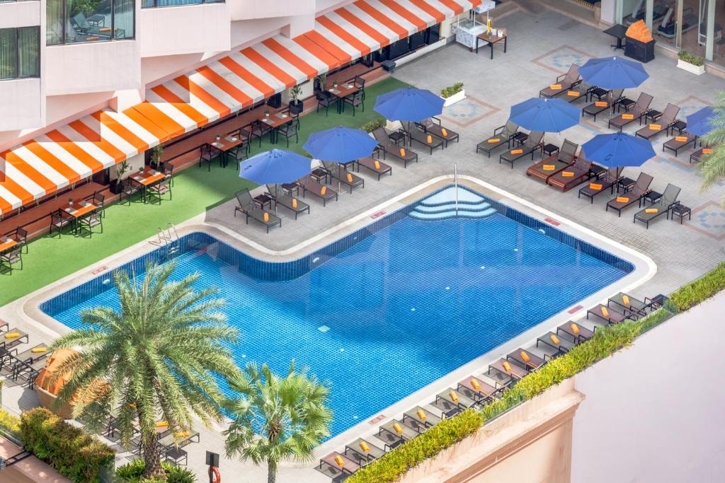 Overhead view of the outdoor pool with palms, blue umbrellas and loungers