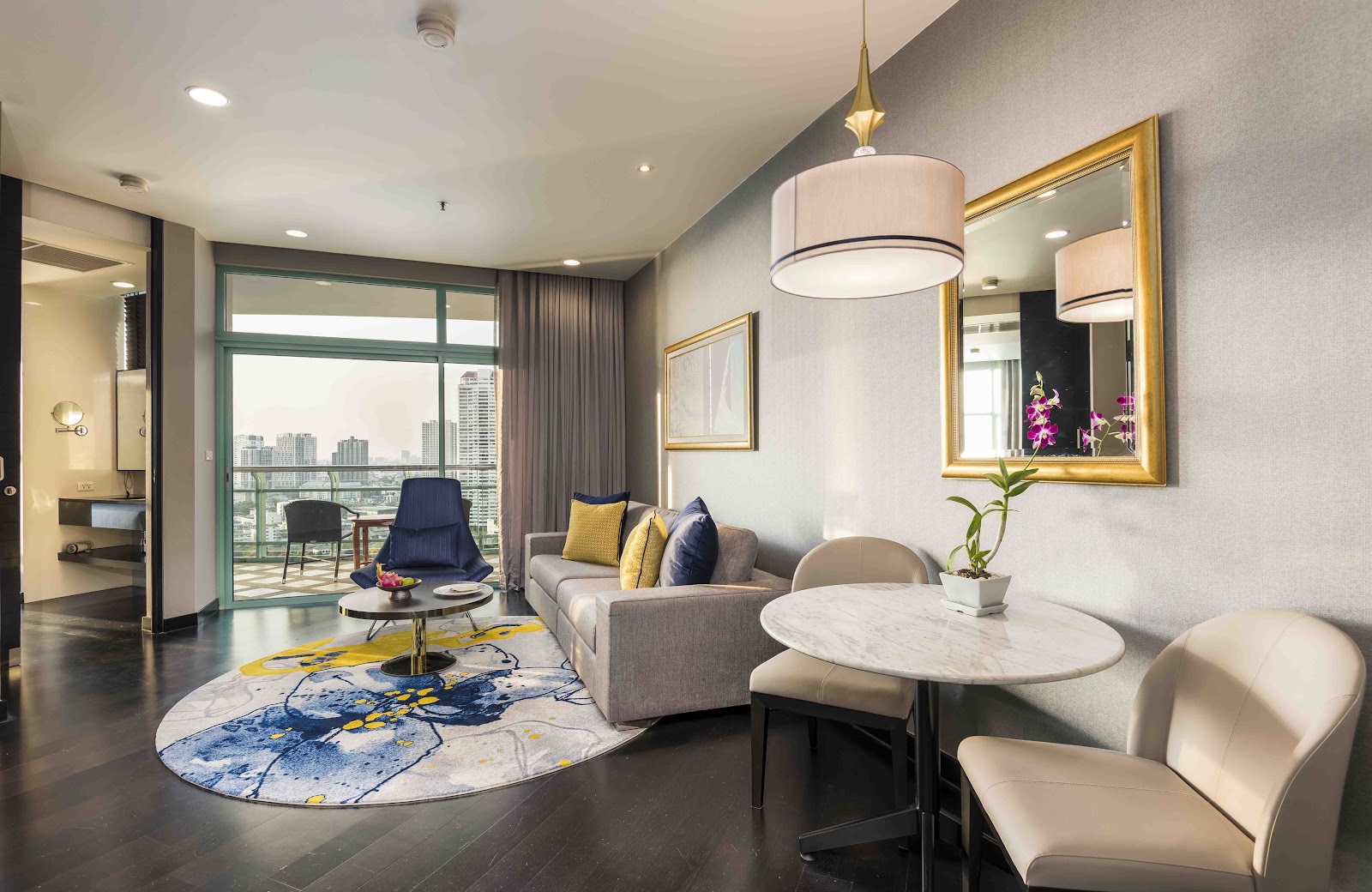 Suite living room with a sofa, dining table and chairs beside windows onto a balcony