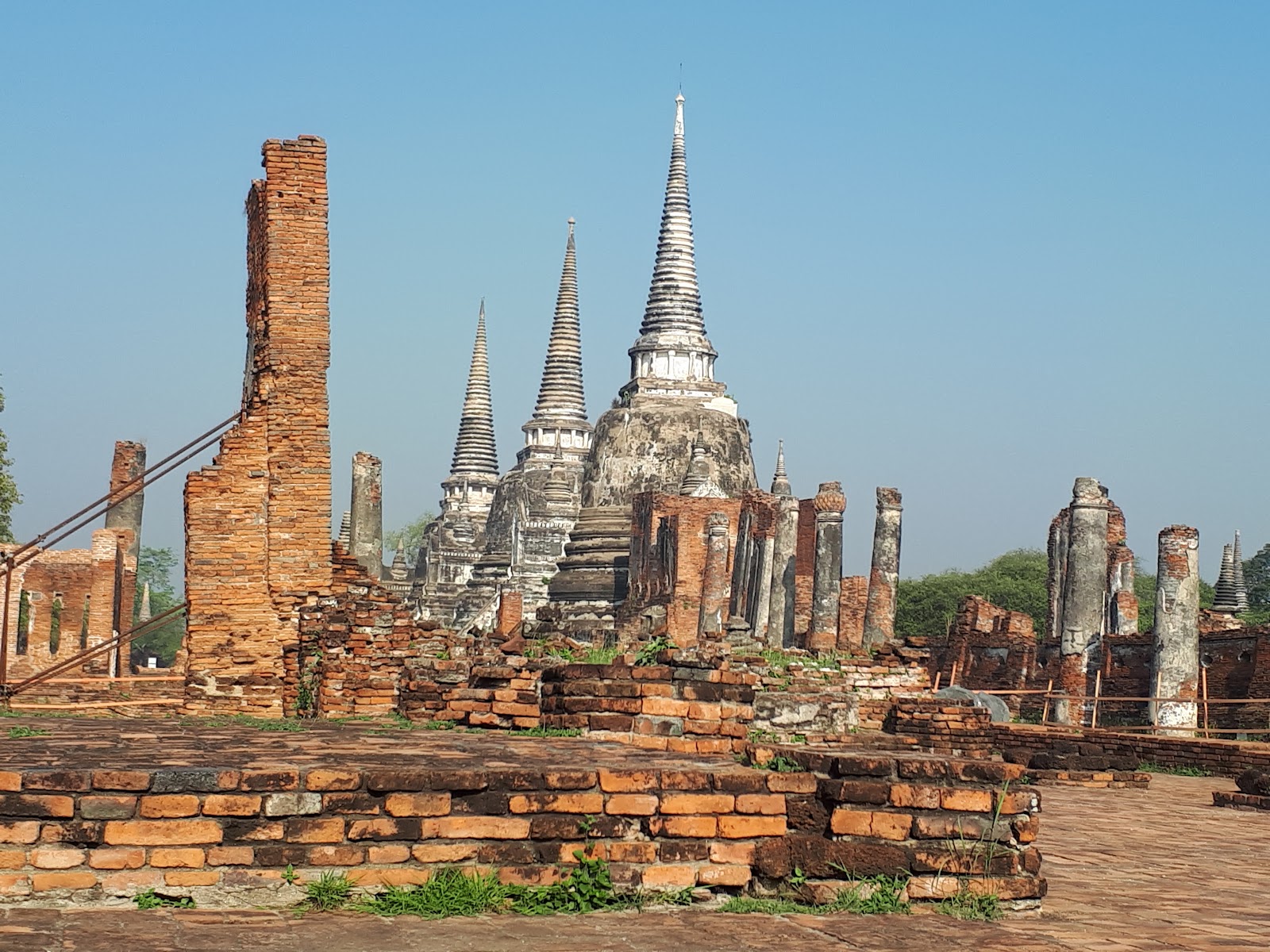 Tall bell-shaped chedis and red-brick ruins under a blue sky in Ayutthaya Historical Park