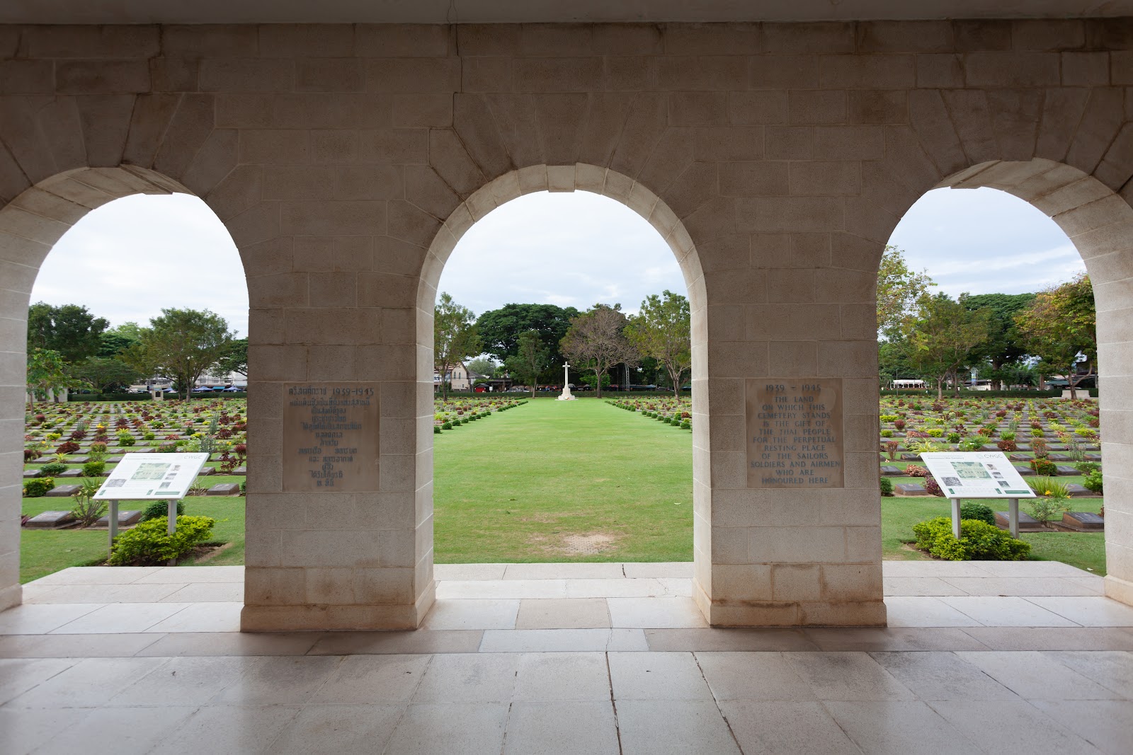 Rows of graves seen through the stone arches of the entrance building at Kanchanaburi War Cemetery
