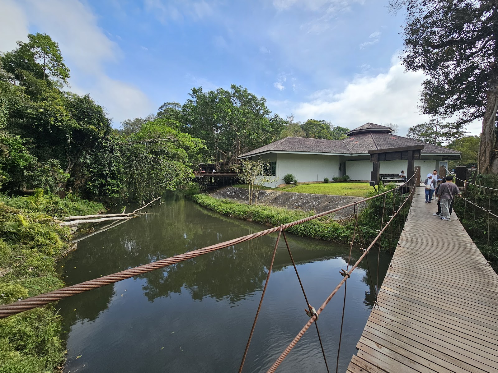 A suspension walkway over a forest stream leading to the Khao Yai visitor center building