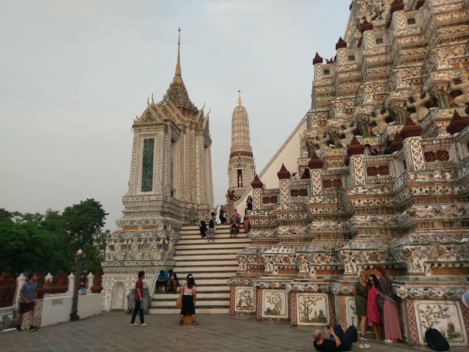 Steps and porcelain-decorated base of Wat Arun's central prang beside a smaller white prang
