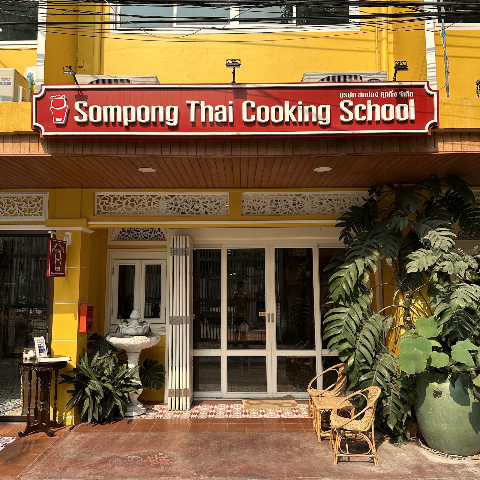 The yellow shophouse front of Sompong Thai Cooking School with its red sign
