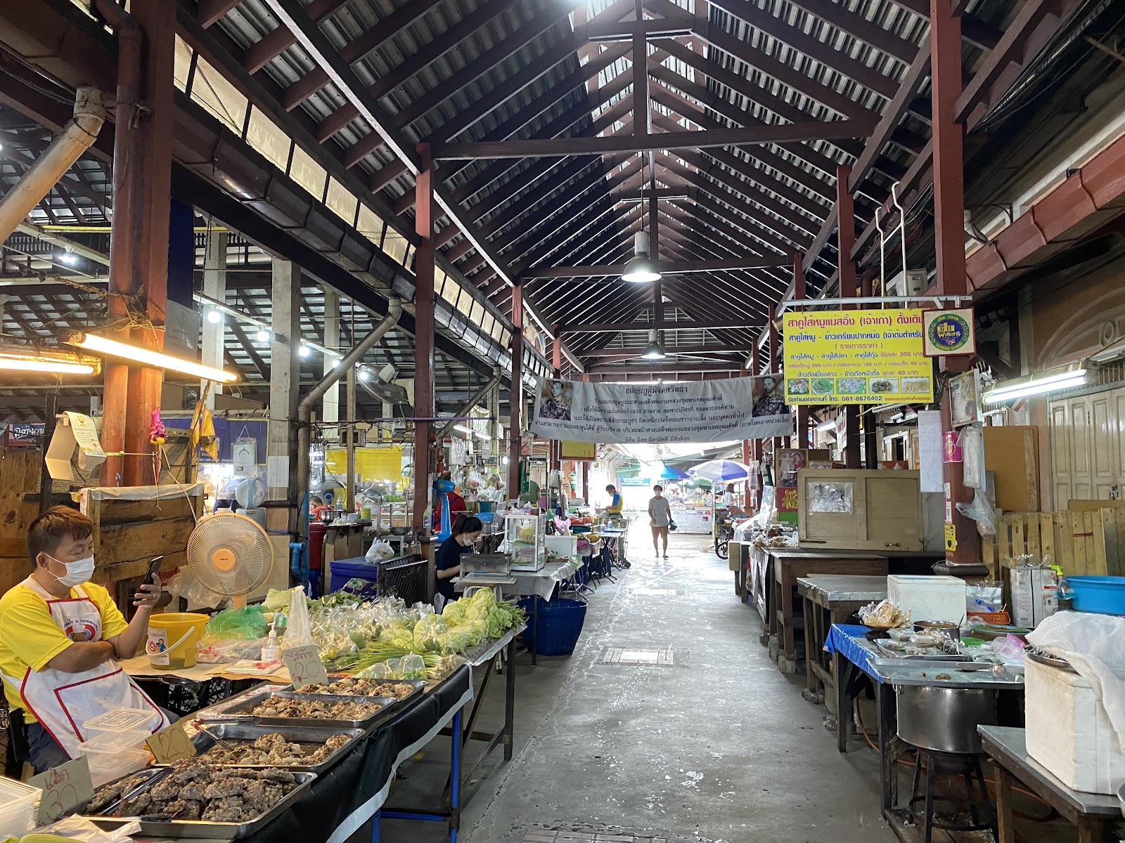 A long covered aisle of food and produce stalls under the timber roof of Nang Loeng Market