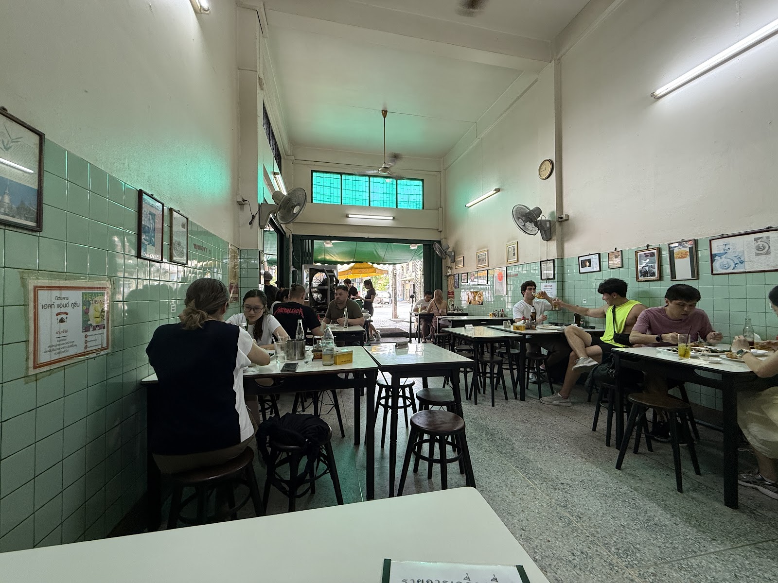 The plain tiled dining room of Jay Fai with tables and ceiling fans