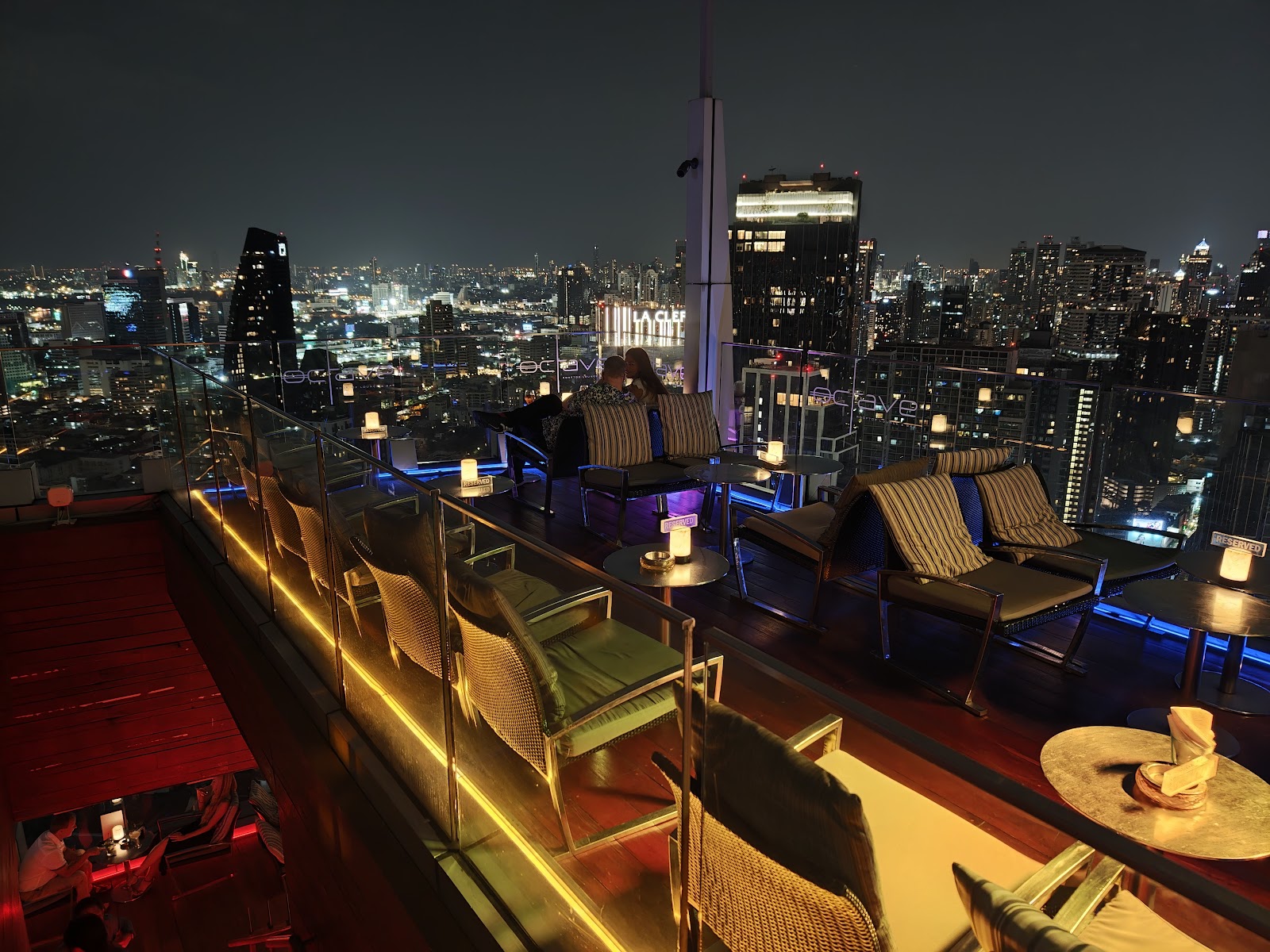 Lounge seating along the edge of the Octave rooftop at night, with Sukhumvit towers behind