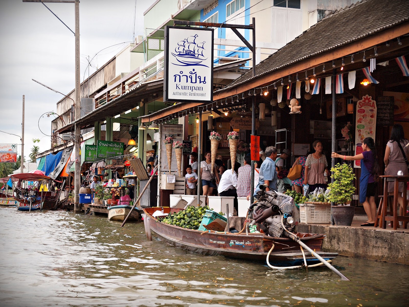 A long-tail boat moored beside canal-side shops at Amphawa Floating Market