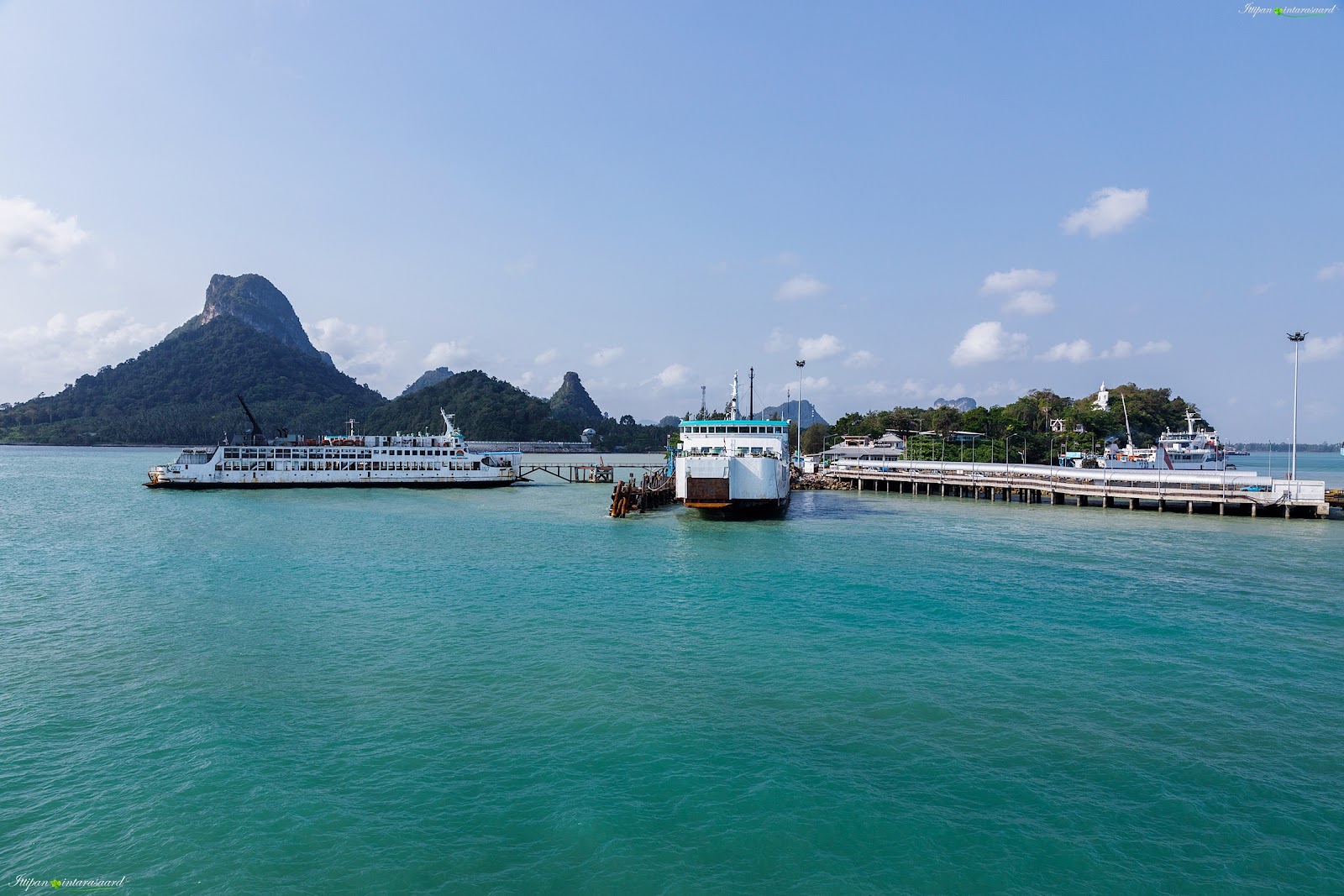 Car ferries moored at the Raja Ferry pier at Donsak with limestone hills behind