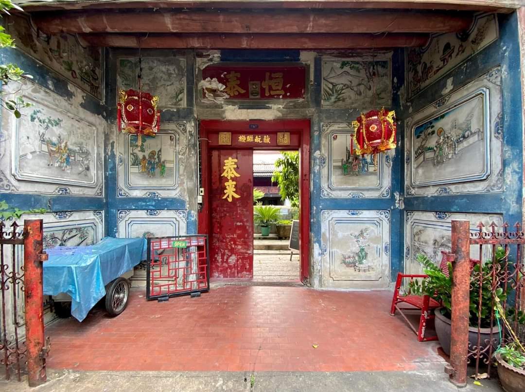 A painted shrine entrance with a red door and lanterns in Talat Noi