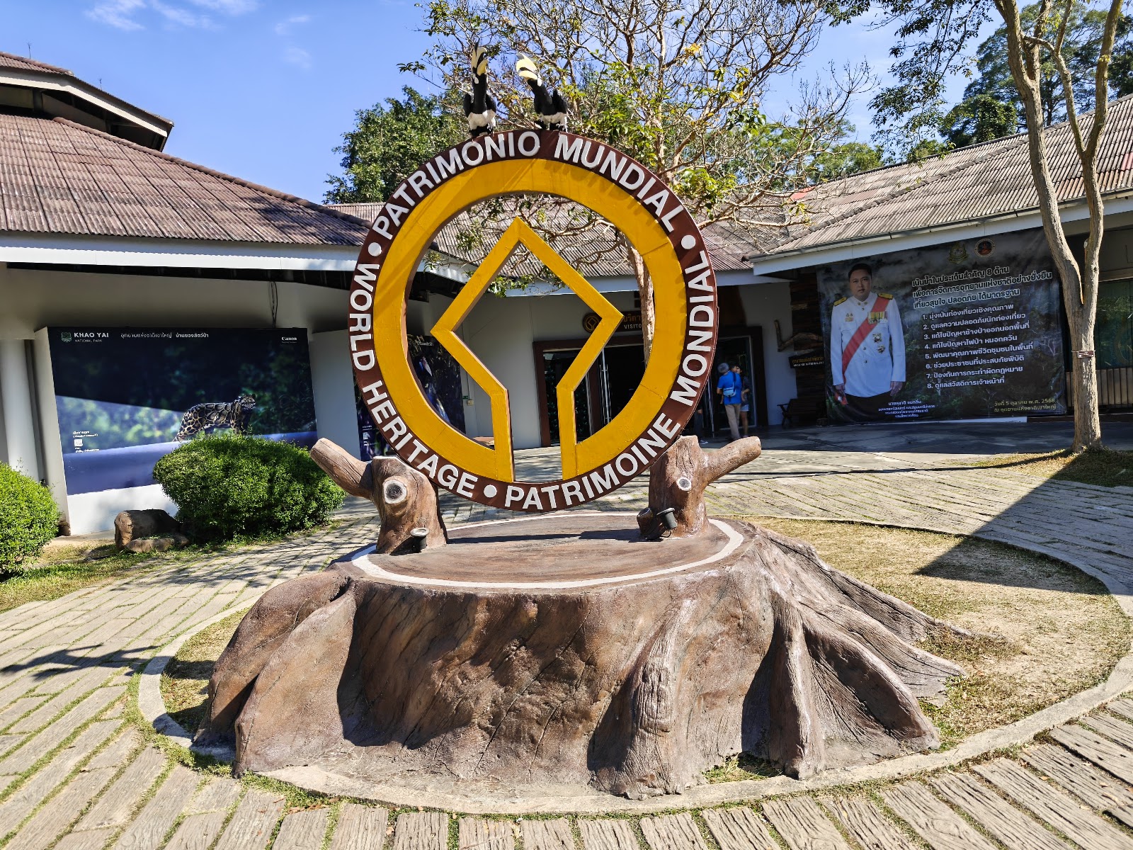 A circular World Heritage emblem on a tree-stump base outside the Khao Yai visitor center