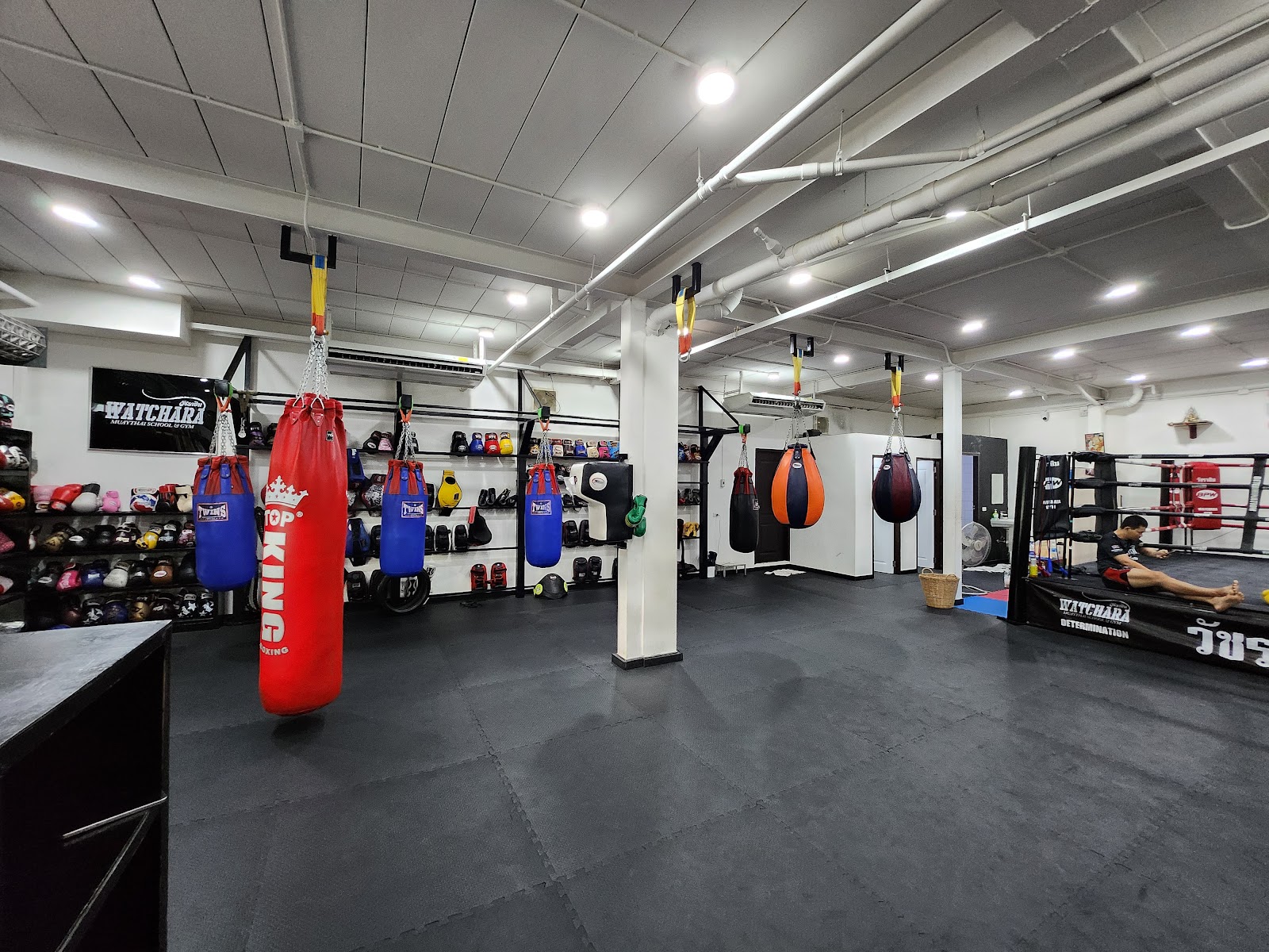 The training floor with heavy bags and a ring at Watchara Muay Thai Gym in Bangkok