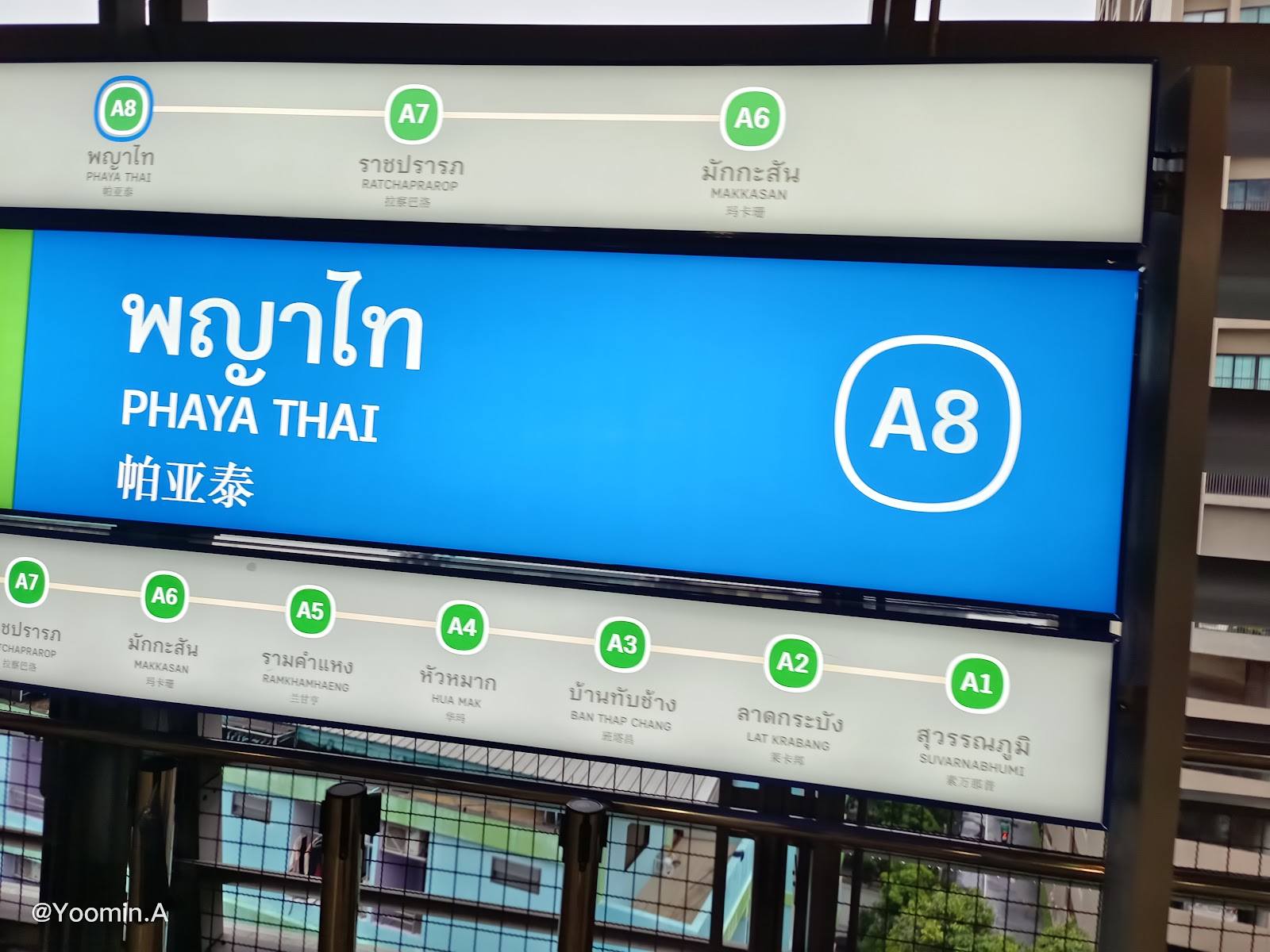 The blue Phaya Thai station sign on the BTS platform showing station code A8