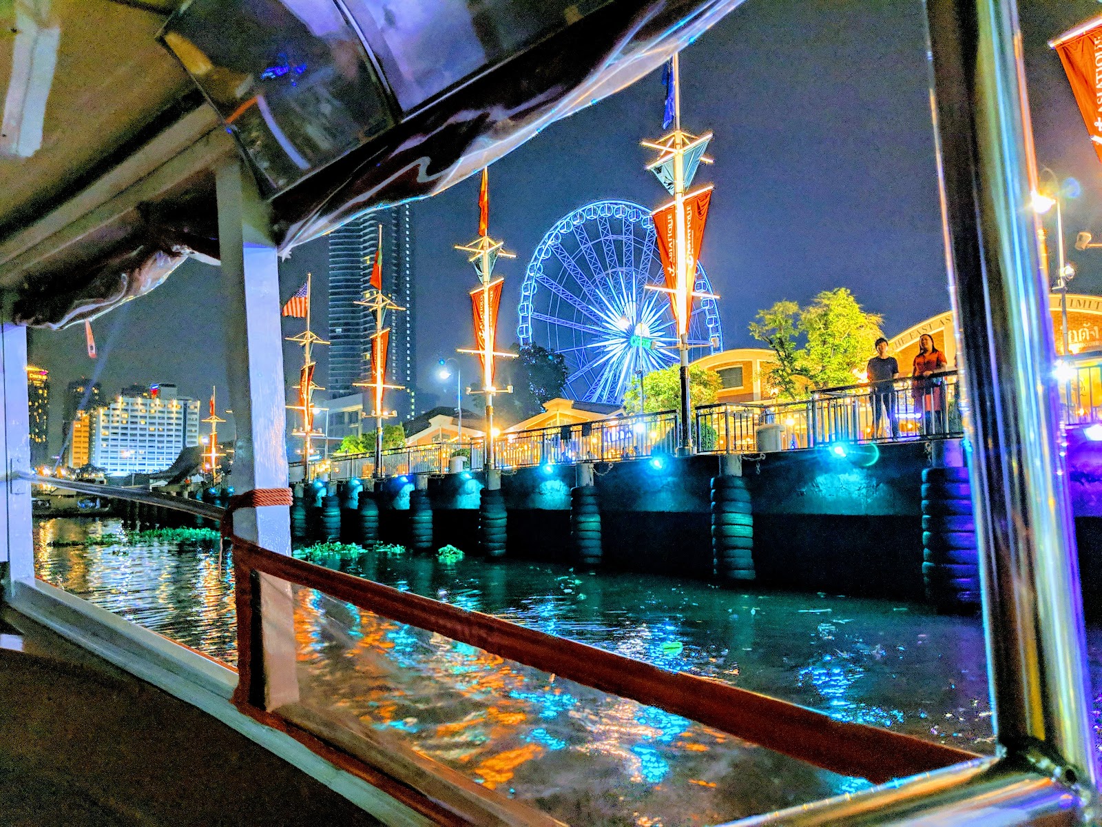 Asiatique The Riverfront and its Ferris wheel lit at night, seen from a boat on the river