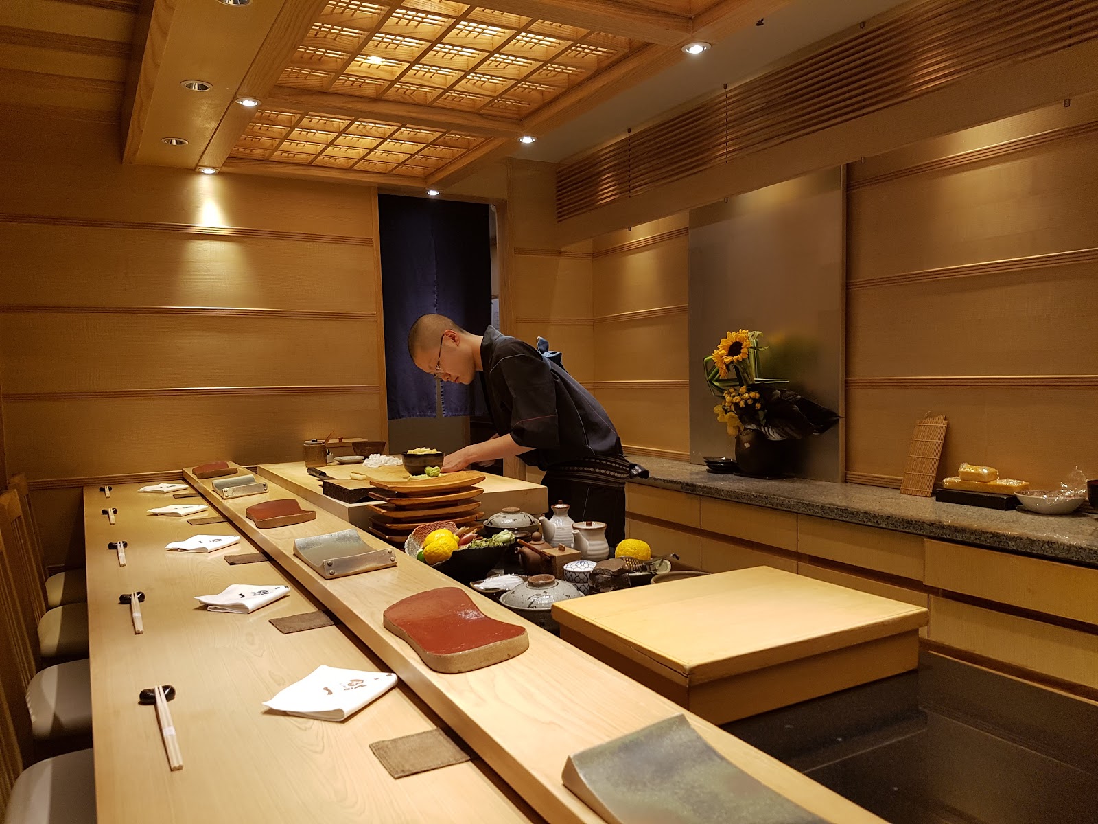 The long pale-wood sushi counter at Ginza Sushi Ichi in Bangkok, with a chef working behind it
