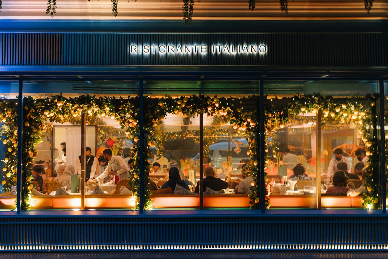 The lit front of Isola by Signor Sassi at night, with lemon branches in the windows