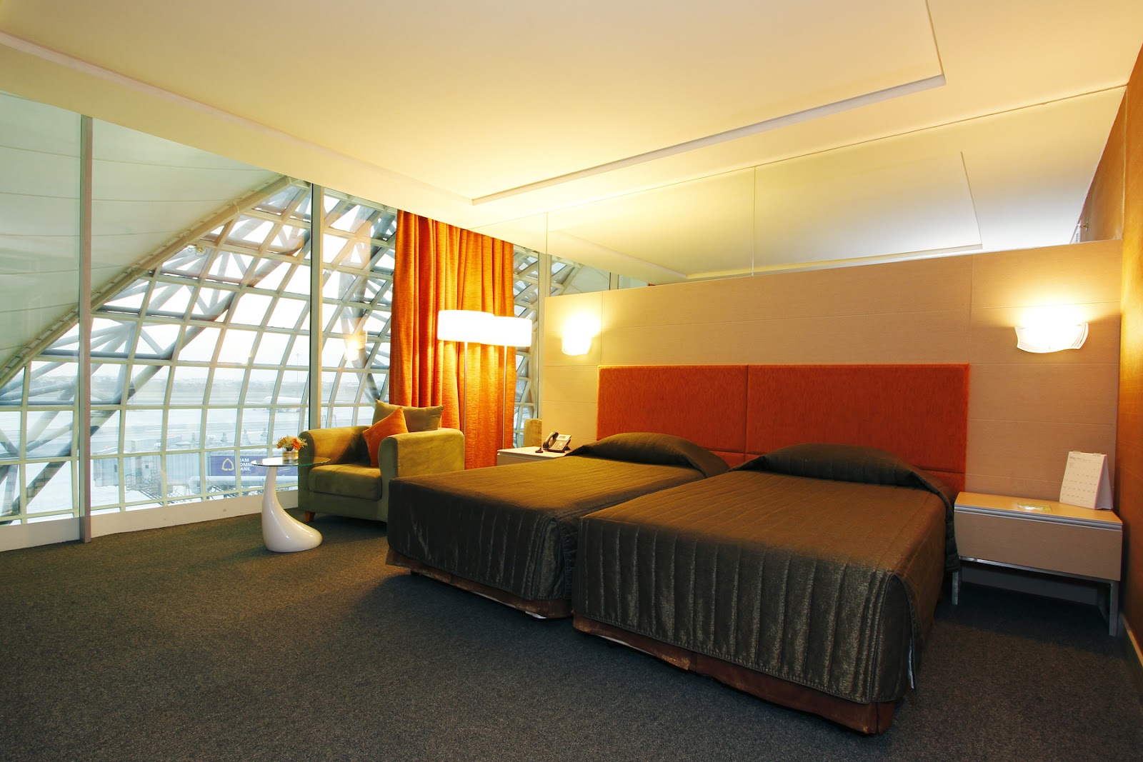 A twin room at the Miracle Transit Hotel with the terminal's curved glass roof behind the beds