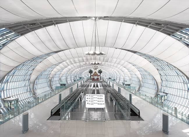The long, curved glass-and-steel concourse of Suvarnabhumi Airport with moving walkways