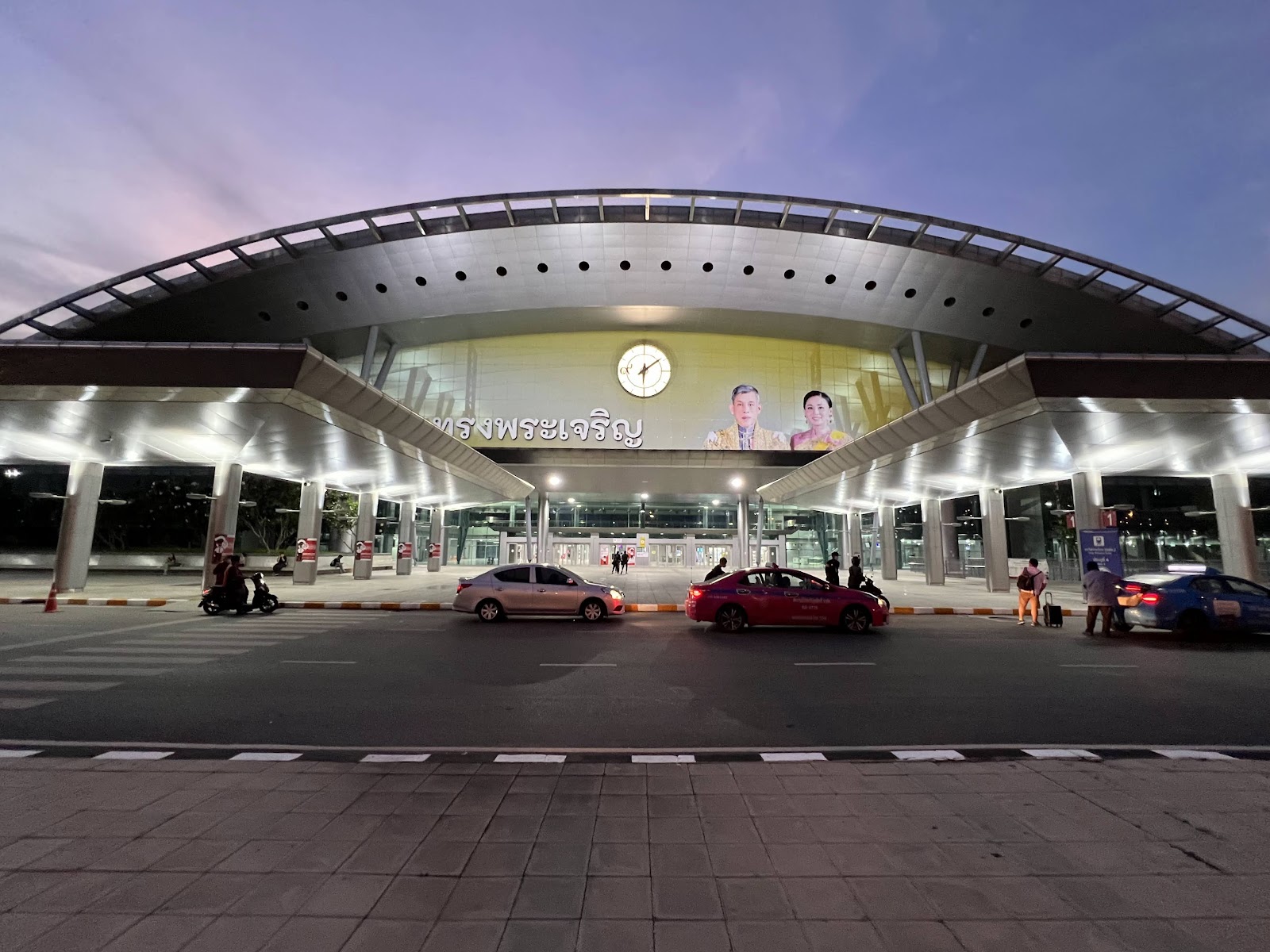 The arched glass and steel entrance of Krung Thep Aphiwat Central Terminal at dusk