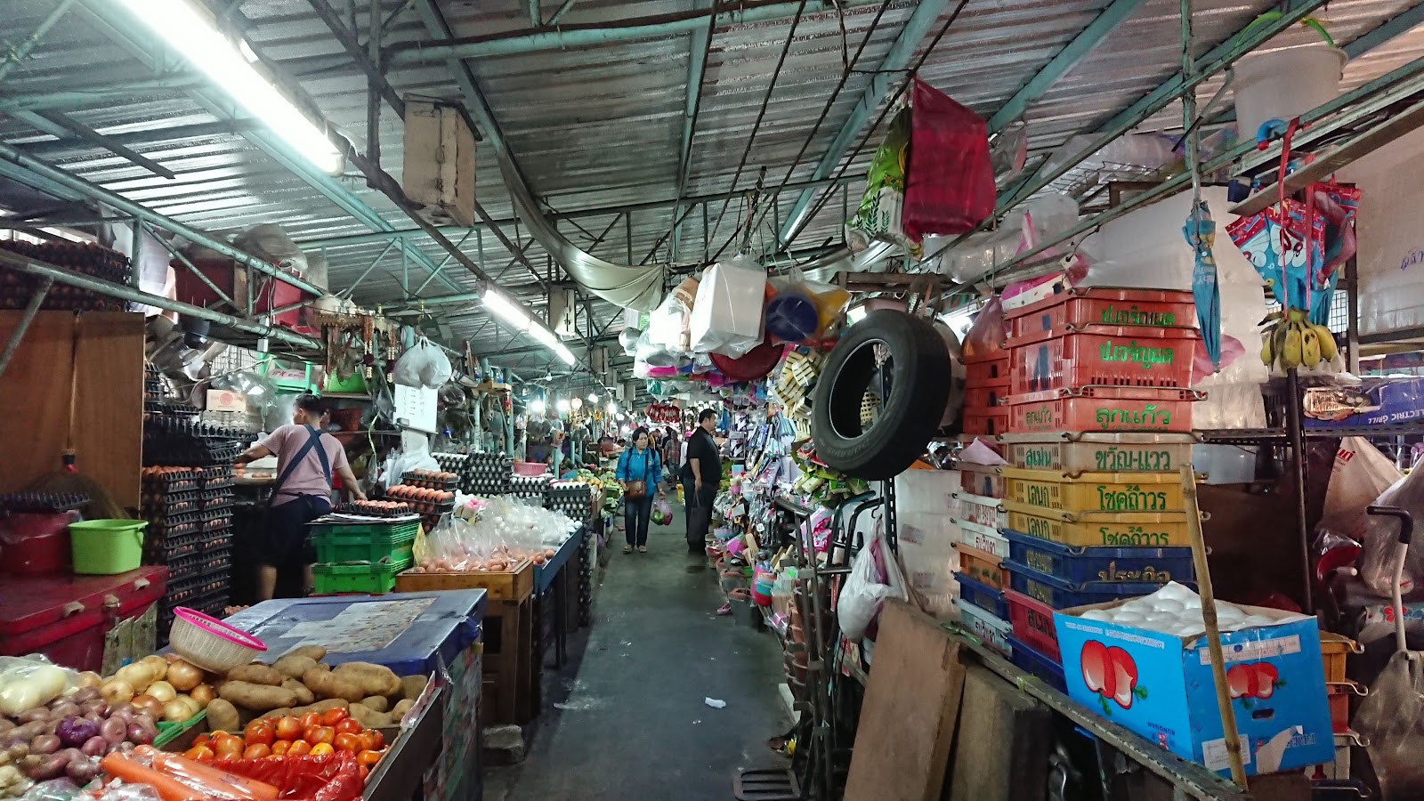 A covered aisle in Khlong Toei Market lined with stalls of produce and household goods