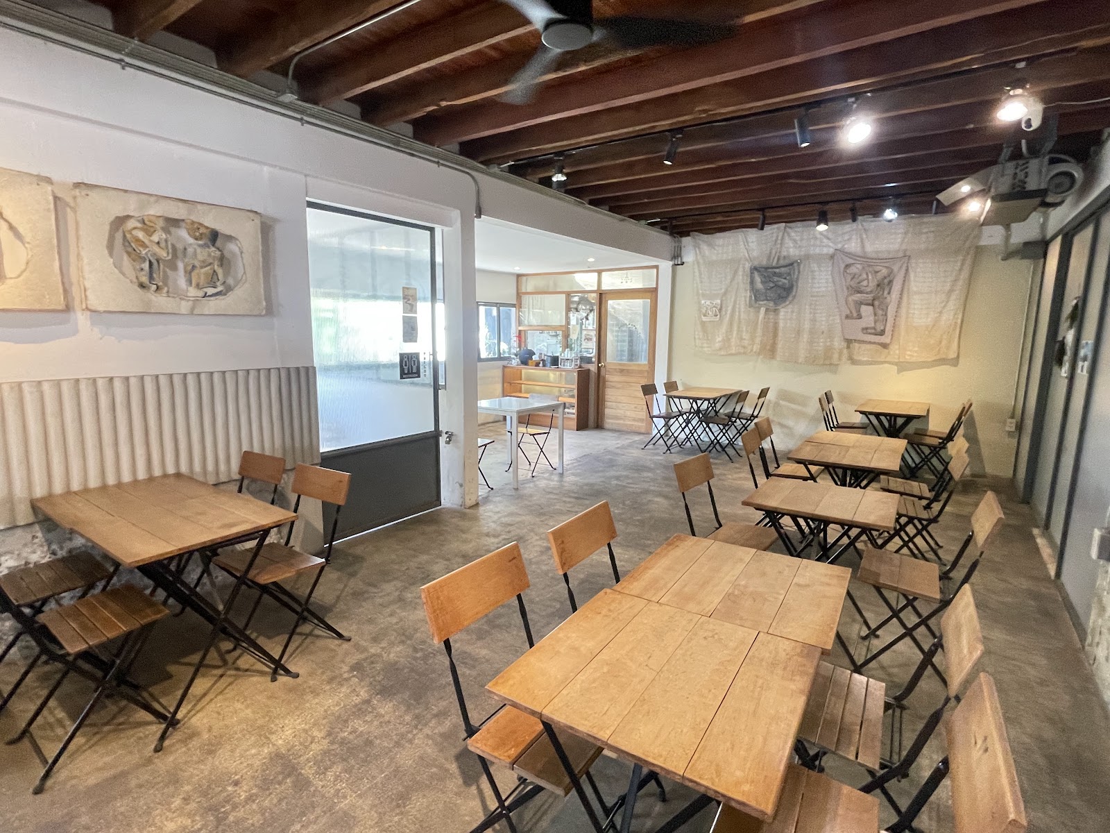 Wooden tables and folding chairs inside the Lilou and Laliart coffee shop
