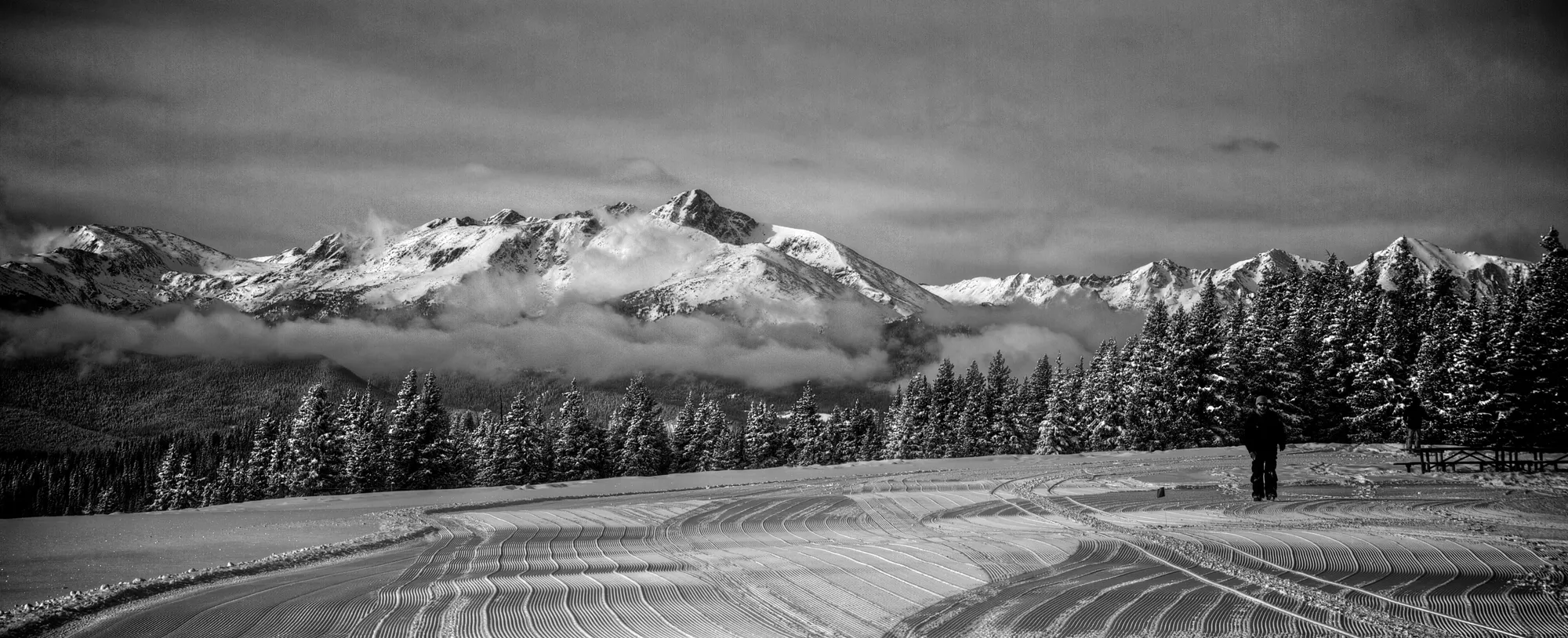 Freshly groomed corduroy at Blue Sky Basin on Vail Mountain, with the snow-covered Gore Range rising above the clouds